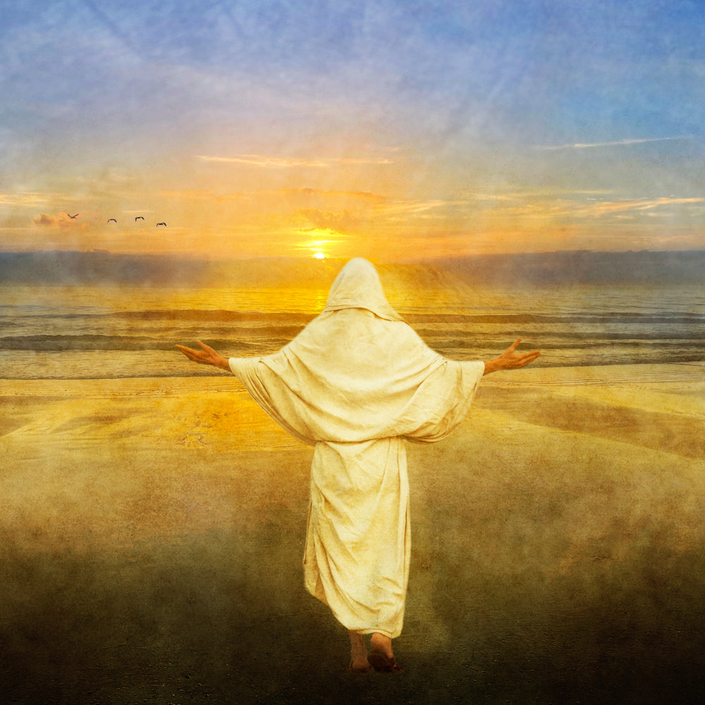 Jesus Christ with his arms spread wide towards the sunset on the beach.