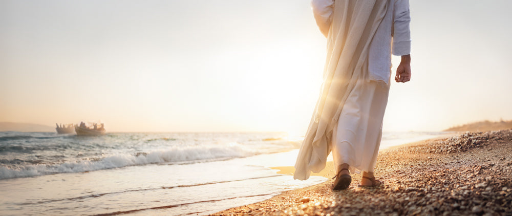 Jesus Christ walking along the shore near a boat full of fishermen.