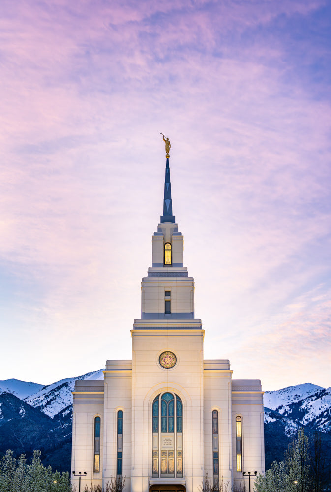 The Layton Utah Temple with the mountains and a purple sky.