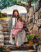 Jesus sitting on steps with little girl in his lap. 