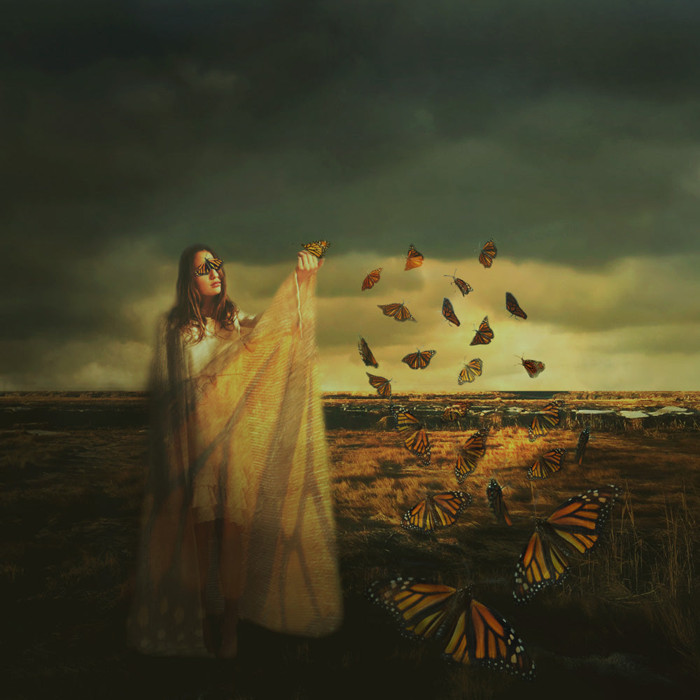 A young woman stands in a field. A butterfly's wings cover her eyes and a trail of butterflies fly to her outstretched hand.