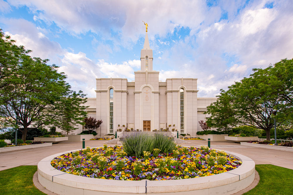 Bountiful Temple with a round flower bed full of yellow flowers standing in the front.