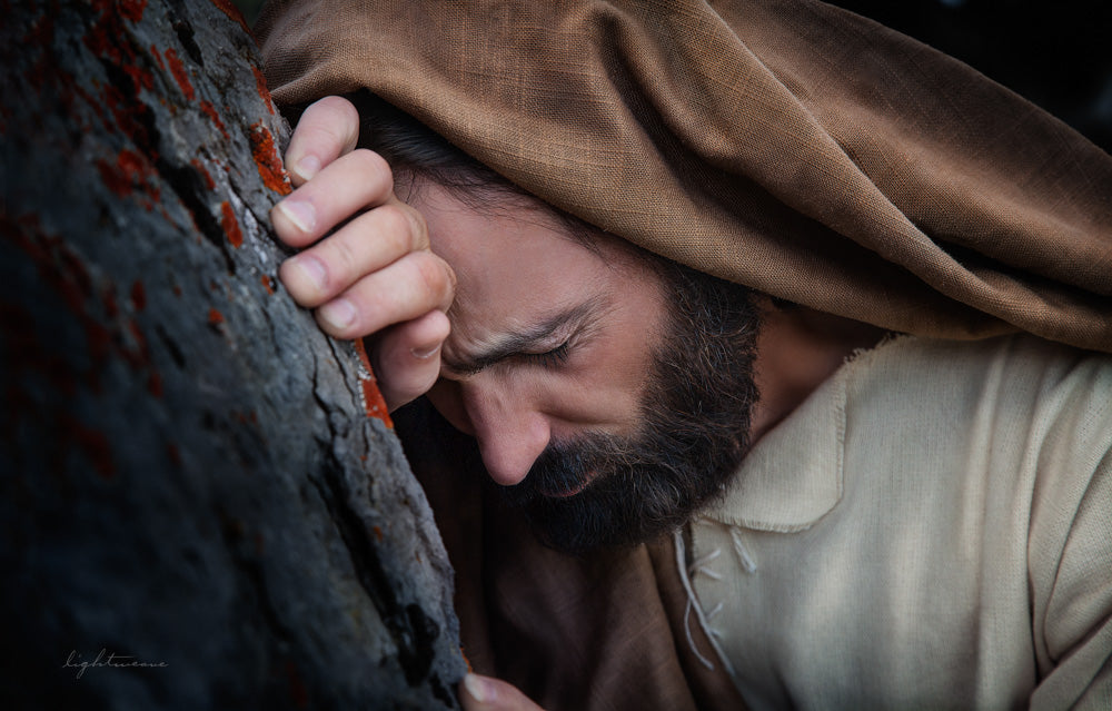 Jesus in gethsemane leaning against tree suffering.