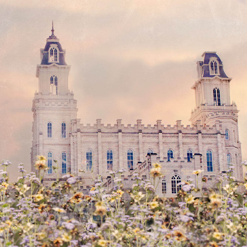 Side view of the Manti Utah Temple with pink and yellow flowers.