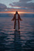 Jesus standing on calm water at sunset. 