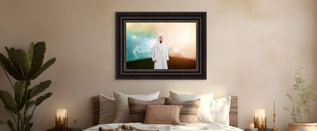 Framed artwork of a robed figure in white standing on a hill under a glowing sky, hung above a bed.