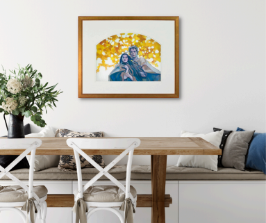 Framed watercolor painting of a romantic couple embracing, with a glowing golden-yellow autumn leaves background, displayed above a wooden dining table.
