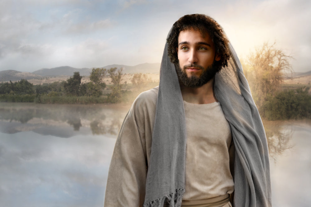 A digital illustration of a man with olive skin, dark curly hair, and a beard, wearing a grey hooded robe in a misty landscape.