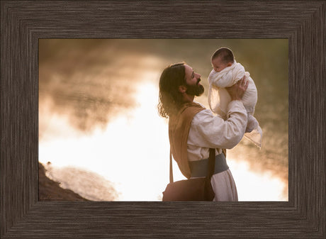 Jesus holding up a baby and smiling.
