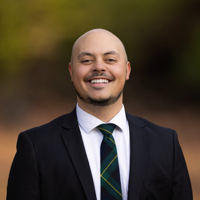 Man wearing a suit and tie with a blurred natural background