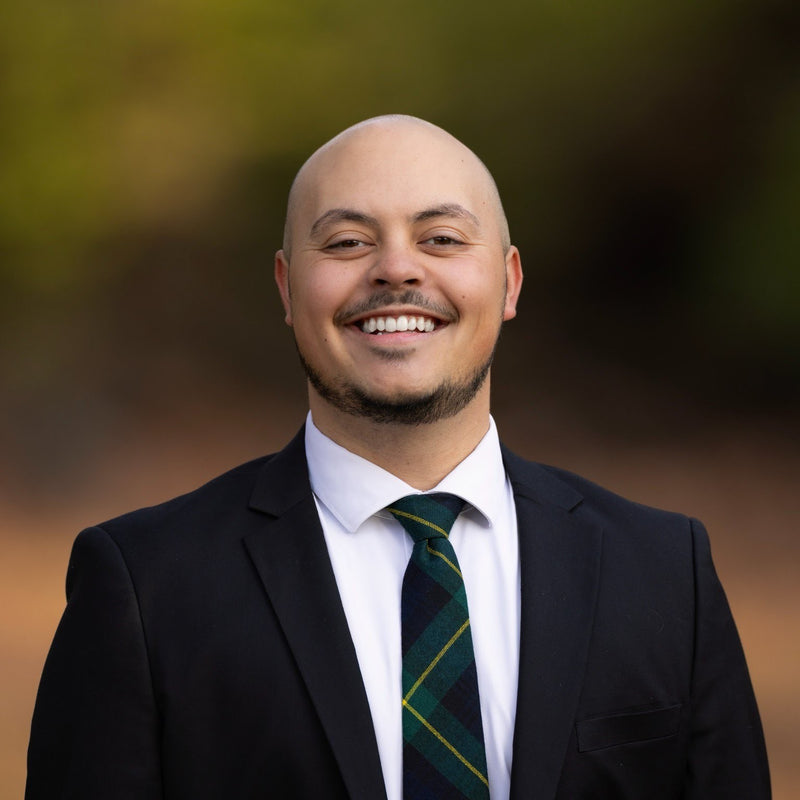 Man wearing a suit and tie with a blurred natural background
