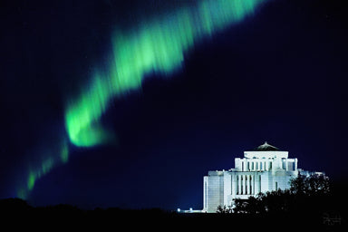 The Cardston Alberta temple at night with a green aurora borealis in the sky.