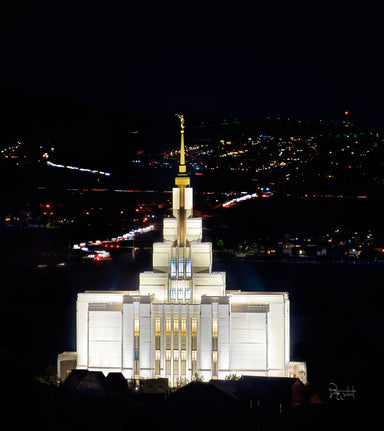 The Saratoga Springs Utah Temple lit up at night with city lights.