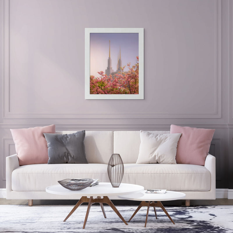 Living room with a beige sofa, pink and gray pillows, and a framed picture of cherry blossoms and a castle.