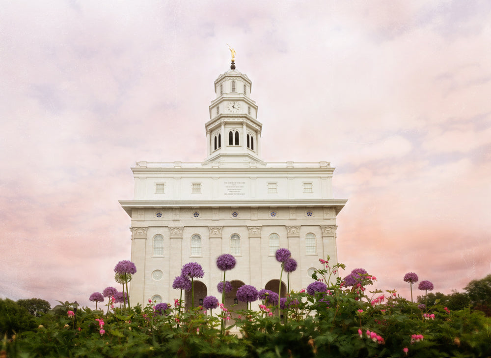 The Nauvoo Illinois Temple with a pink sky and purple flowers.