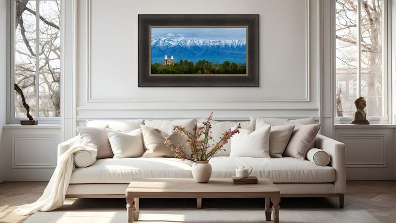 Living room with a beige sofa, coffee table, and framed mountain landscape painting.