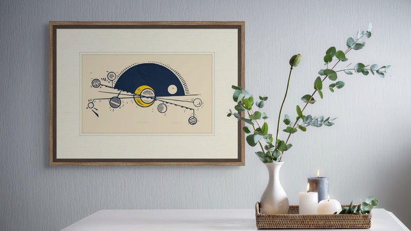 Framed artwork on a wall with a decorative table below featuring a vase, candles, and plants.