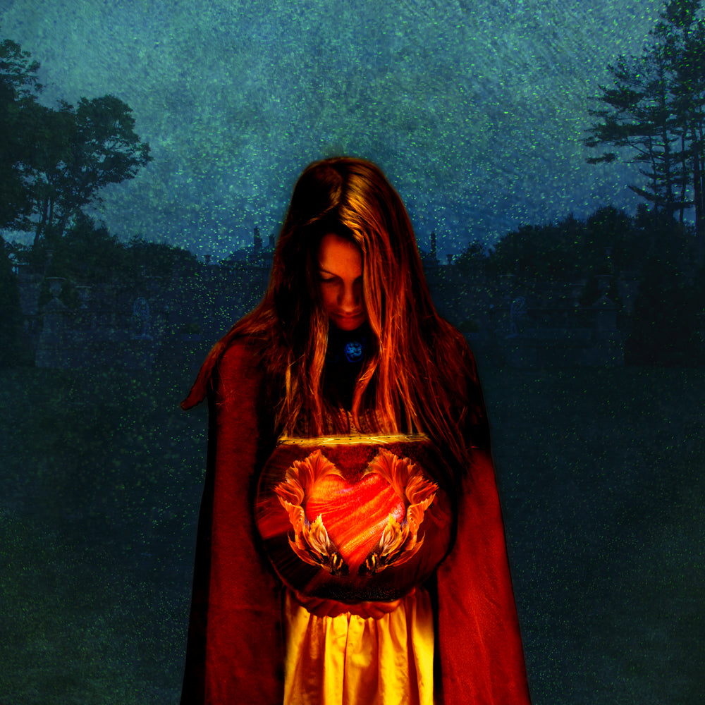 A young woman stands in the dark holding a glowing heart.