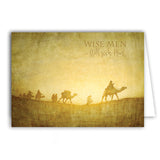 A Christmas card showcasing a desert scene with camels and people in a caravan.