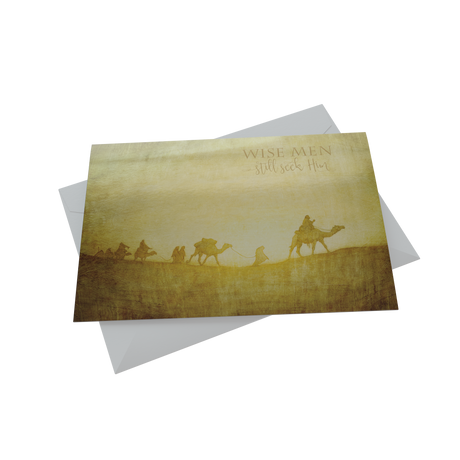 A Christmas card depicting a caravan scene with camels and people, celebrating the holiday in a desert setting.