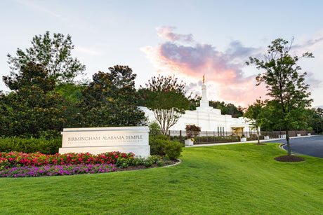 Birmingham Temple at an angle, with a focus on the entrance sign. Pink clouds peek over the top of the temple.