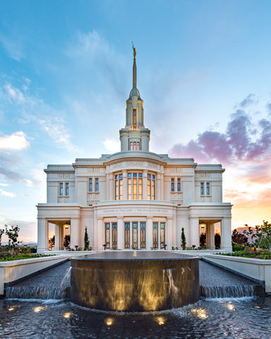 Photo of the Payson Temple with a focus on a flowing water fountain. The sun is setting in the background.