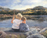 Two young children sitting on a rock looking out at a lake. 