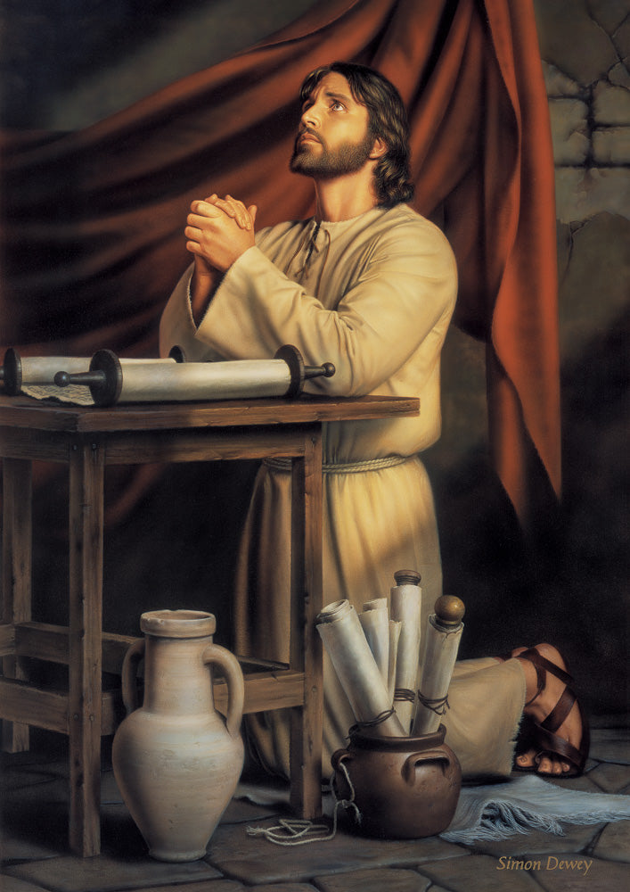 Jesus kneeling beside a table praying surrounded by scripture scrolls.
