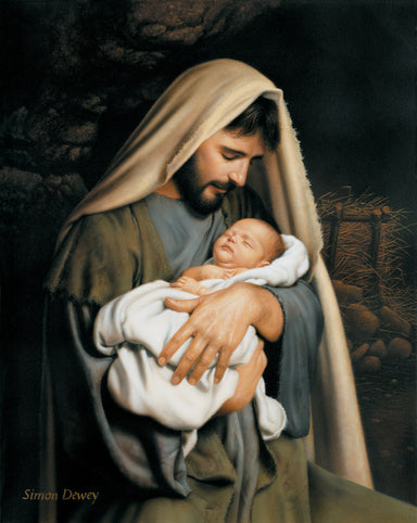 Joseph holding baby Jesus in his arms with the manger in the background.
