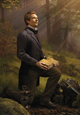 Man kneeling in a forest holding a glowing box with beams of sunlight filtering through trees.