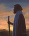 Jesus Christ as the good shepherd standing with a staff at sunset. 